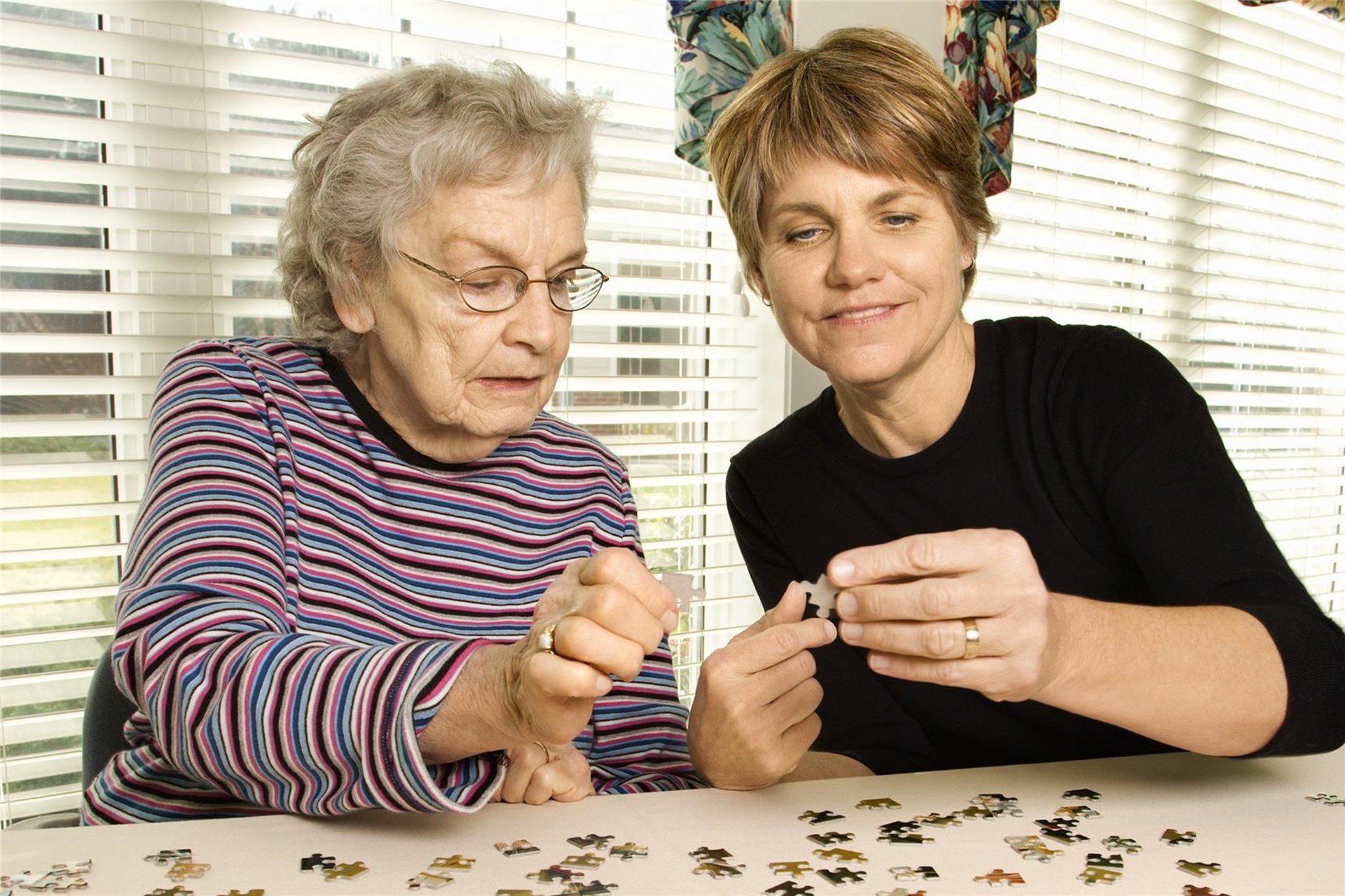 junge Frau sitzt mit älterer Frau an einem Tisch